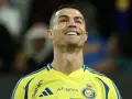 Uśmiechnięty Cristiano Ronaldo w żółtej koszulce Al Nassr. To właśnie w tym klubie gra Ronaldo.
