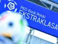 Niebieska tablica z logo PKO Bank Polski i napisem EKSTRAKLASA. W tle piłka nożna, gdy terminarz ekstraklasy.