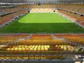 Pusta trybuna stadionu Jagiellonii, z żółtymi i czerwonymi siedzeniami. Pojemność obiektu robi wrażenie.