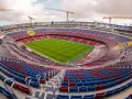 Stadion de la Cartuja w budowie, z widocznymi dźwigami i częściowo wykończonymi trybunami w kolorach czerwonym i niebieskim.