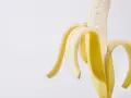 Połówka obranego banana, idealna przekąska przed czy po treningu, dostarcza energii.