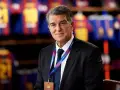 Uśmiechnięty prezes Barcelony, Joan Laporta, w garniturze, z identyfikatorem FC Barcelona na szyi.