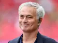 Uśmiechnięty José Mourinho, były trener Realu Madryt, z siwymi włosami i słuchawką w uchu.