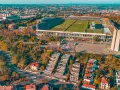 Widok z lotu ptaka na imponujący stadion, największy stadion w Europie, otoczony jesienną zielenią i nowoczesną zabudową.