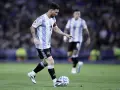 Lionel Messi w koszulce Argentyny prowadzi piłkę, gotowy do zdobycia kolejnych bramek. Fani zastanawiają się, ile goli ma Messi.
