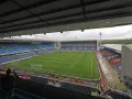 Widok na murawę i trybuny stadionu Ewood Park. Puste miejsca na niebieskich i czerwonych siedzeniach.