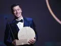 Uśmiechnięty Robert Lewandowski w eleganckim garniturze odbiera nagrodę, być może Złotą Piłkę.