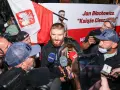 Jan Błachowicz, "Książę Cieszyński", mistrz UFC, otoczony przez fanów i dziennikarzy z polską flagą. Polacy w UFC świętują sukces.