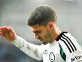 Piłkarz w białej koszulce z czarnymi pasami, zamyślony. Czy jego zarobki w 1 lidze są adekwatne do wysiłku?