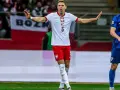 Piłkarz w białej koszulce z orłem, numer 5. Jan Bednarek po kontuzji wraca do gry, gestem prosi o spokój.