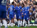 Piłkarze Chelsea w niebieskich strojach rozmawiają na boisku. Widać numery 29, 20 i 10.