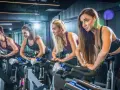 Cztery kobiety ćwiczą na rowerach stacjonarnych. Ile powinien trwać trening cardio? To zależy od celów, ale często 30-60 minut to dobry punkt wyjścia.