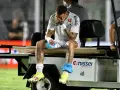 Neymar siedzi na wózku golfowym, zakrywając twarz dłońmi. Jego kontuzja jest widoczna, a zawodnik wygląda na zrozpaczonego.