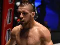 Zacięty zawodnik MMA z charakterystyczną fryzurą i ochraniaczem na zęby, gotowy do walki.