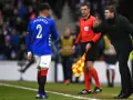 Piłkarz Rangers, Tavernier, słucha trenera. Sędzia liniowy z chorągiewką stoi obok.