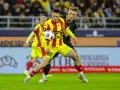 Piłkarz w żółto-czerwonej koszulce walczy o piłkę z rywalem w czarnym stroju. Intensywny przebieg: Pogoń Szczecin – Korona Kielce.