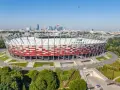 PGE Narodowy, jeden z największych stadionów w Polsce, w otoczeniu zieleni i warszawskiej panoramy.