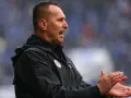 Trener Zagłębia Lubin, w czarnej kurtce, z otwartymi ustami i klaszczącymi dłońmi, motywuje drużynę.