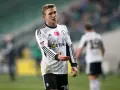 Kuba Rzeźniczak w białej koszulce z czarnymi pasami, na boisku.