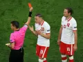 Sędzia pokazuje czerwoną kartkę w siatkówce. Piłkarz z numerem 20 protestuje, obok stoi kolega z numerem 10.