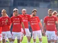 Piłkarze Wisły Kraków w czerwonych strojach, z numerami na koszulkach i spodenkach, świętują. W tle trybuny. #wisla #krakow #transfery