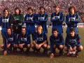 Drużyna piłkarzy z Bergamo w niebiesko-czarnych strojach, gotowa do gry na tle trybun pełnych kibiców.