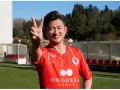 Uśmiechnięty Kazuyoshi Miura, najstarszy piłkarz na świecie, pokazuje znak pokoju na boisku.
