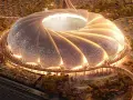 Futurystyczny stadion, który może być najładniejszy na świecie, z falującym dachem i oświetlonymi detalami, otoczony zielenią i tłumem ludzi.