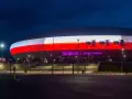 Tauron Arena Kraków nocą, z podświetloną fasadą w barwach narodowych. Obiekt mieści 15 tysięcy widzów, co czyni go jednym z największych w Polsce.
