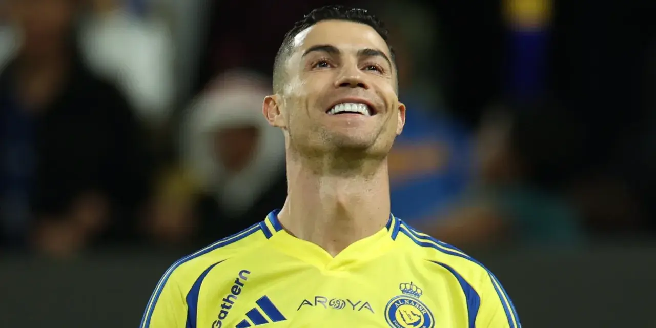 Uśmiechnięty Cristiano Ronaldo w żółtej koszulce Al Nassr. To właśnie w tym klubie gra Ronaldo.