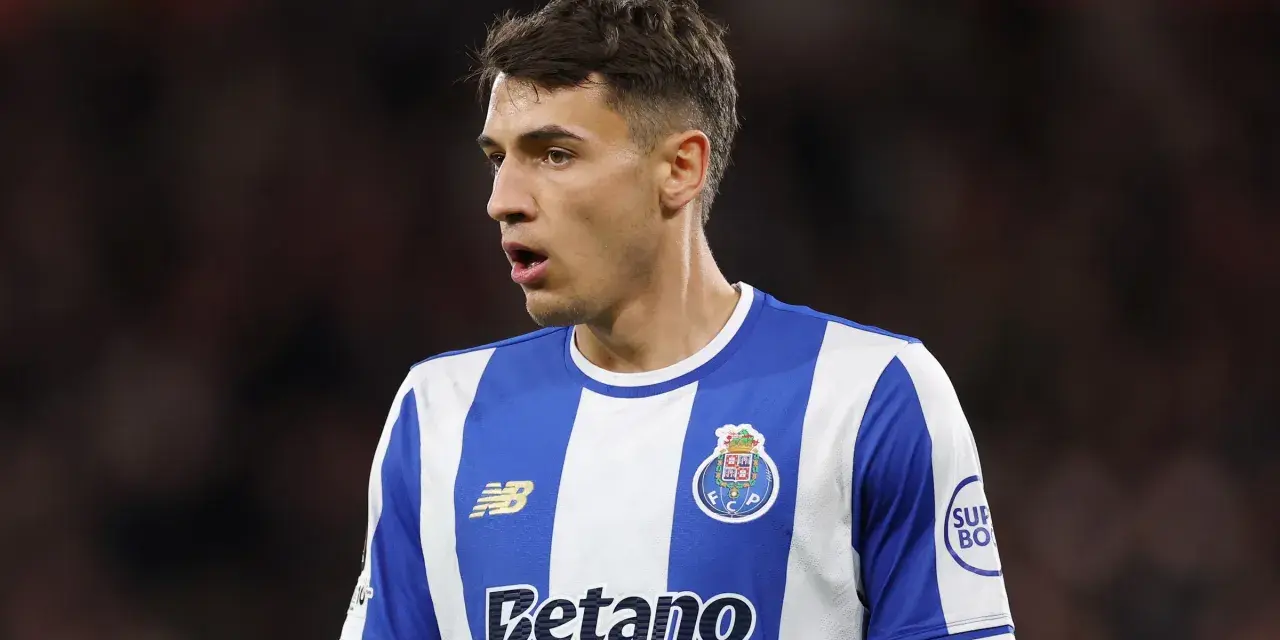 Piłkarz w niebiesko-białej koszulce FC Porto, gdzie gra Kiwior, z uwagą obserwuje boisko.