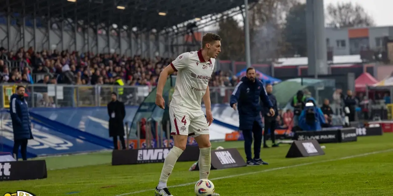 Piłkarz w białej koszulce z numerem 4, przygotowuje się do gry podczas meczu Raków Częstochowa – Widzew Łódź.