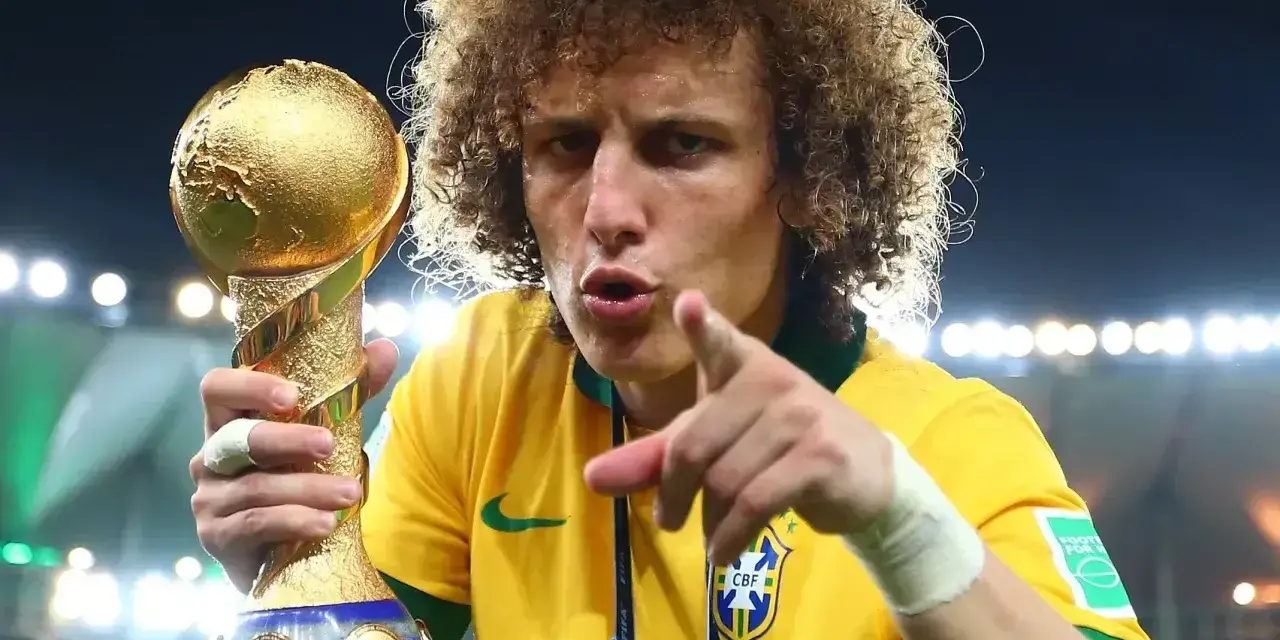 Piłkarz z Brazylii, z bujną fryzurą, triumfalnie trzyma złoty puchar Konfederacji FIFA.