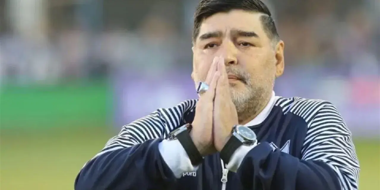 Diego Maradona na co zmarł? Legenda futbolu z dłońmi złożonymi do modlitwy, w charakterystycznej bluzie.