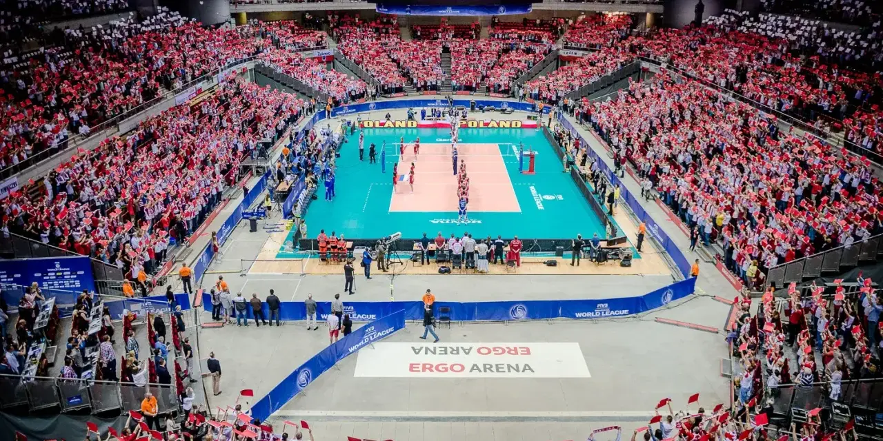 Widownia Ergo Areny, wypełniona kibicami z flagami Polski, dopingująca mecz siatkówki. Ogromna pojemność hali robi wrażenie.