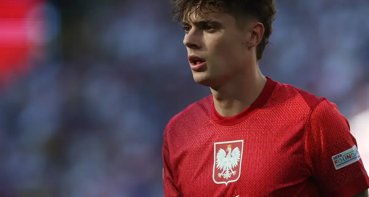 Młody piłkarz w czerwonej koszulce z orłem, symbolizujący polską reprezentację. Jego wzrost i determinacja na boisku budzą nadzieję na przyszłe sukcesy.