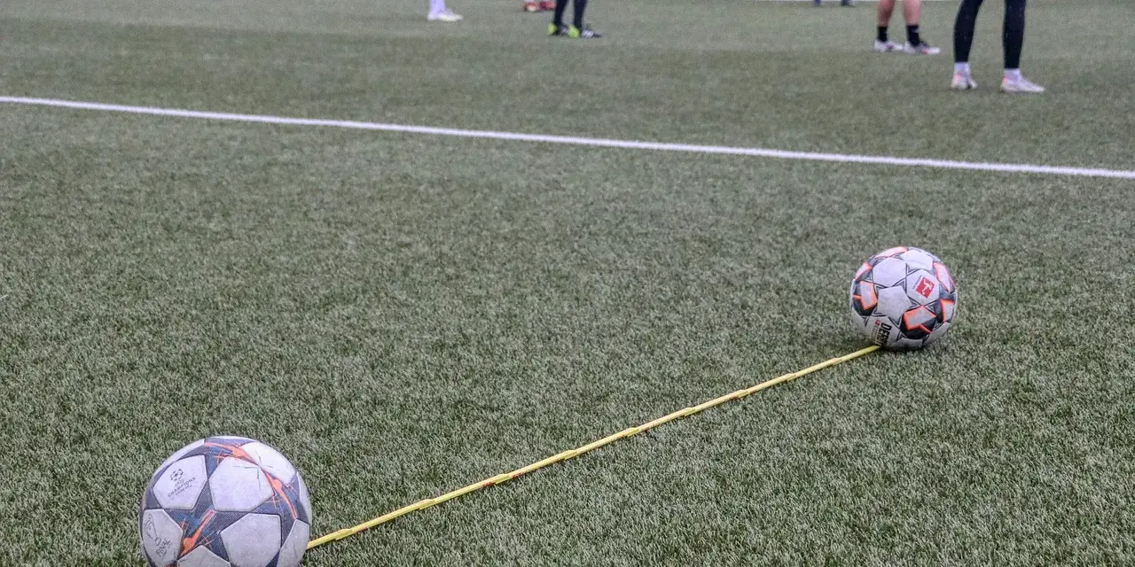 Dwa piłki na boisku połączone żółtą linką. Trening, który pokazuje, jak nie być profesjonalnym piłkarzem.
