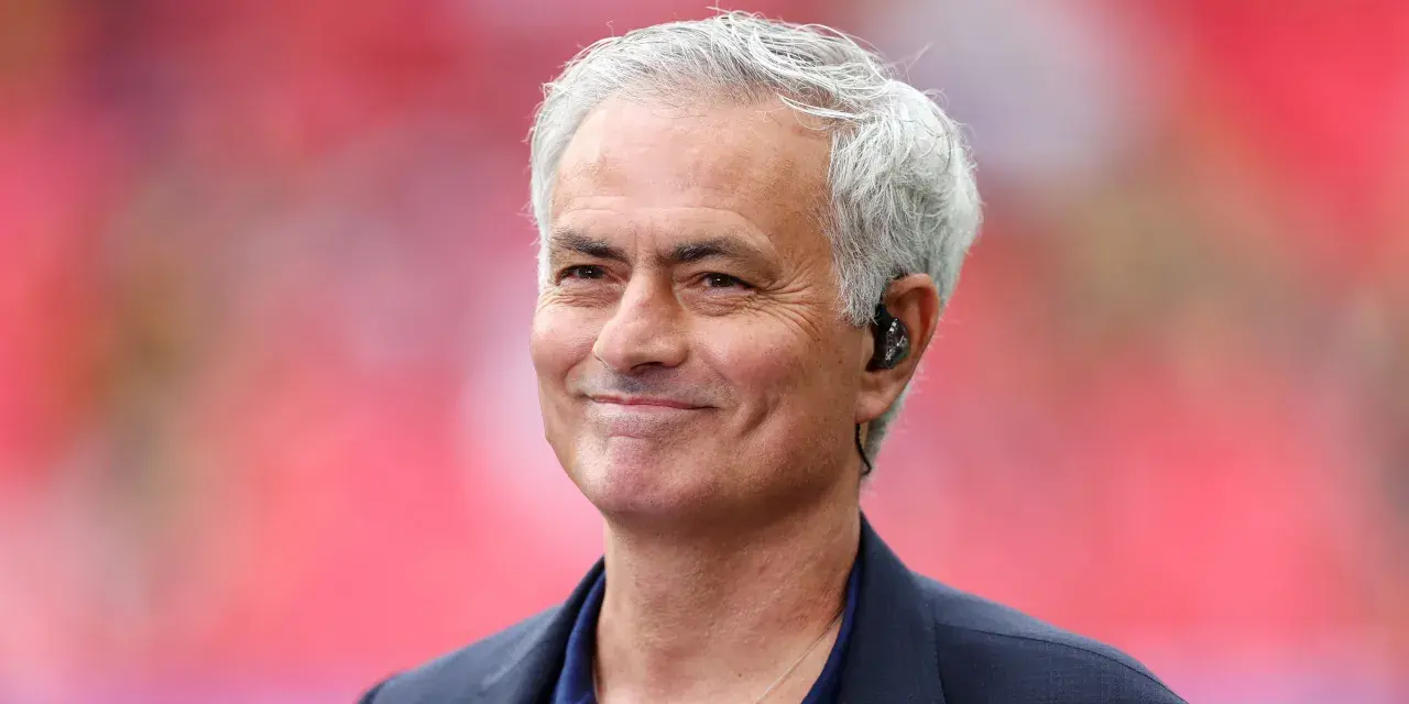 Uśmiechnięty José Mourinho, były trener Realu Madryt, z siwymi włosami i słuchawką w uchu.