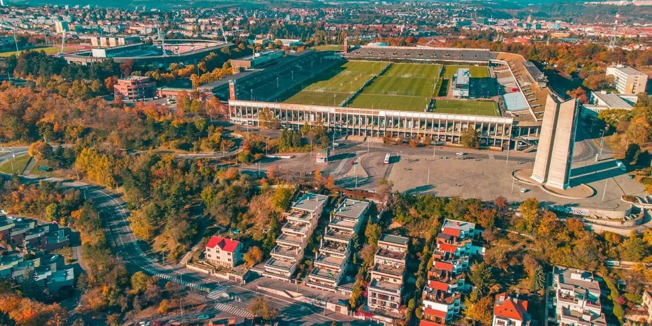 Widok z lotu ptaka na imponujący stadion, największy stadion w Europie, otoczony jesienną zielenią i nowoczesną zabudową.