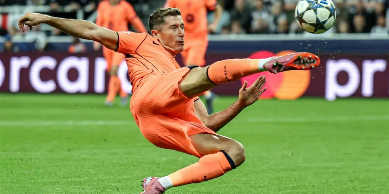 Piłkarz w pomarańczowym stroju wykonuje akrobatyczne kopnięcie do piłki. To Robert Lewandowski, który gra w Lidze Mistrzów.