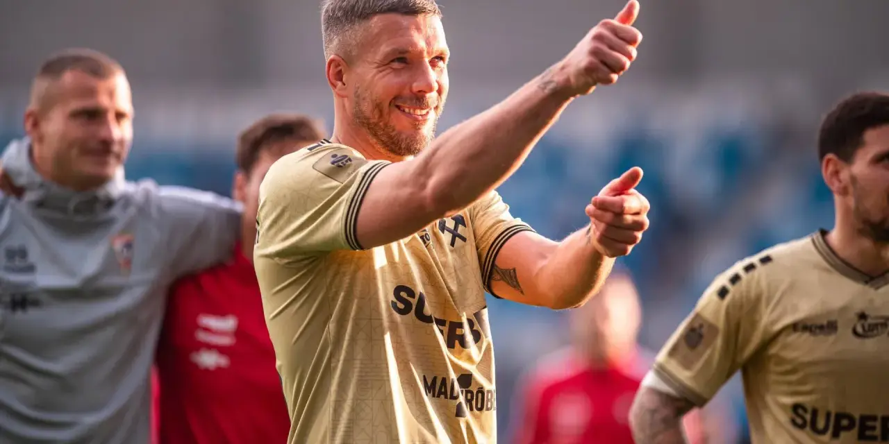 Uśmiechnięty Lukas Podolski pokazuje kciuk w górę, jakby podsumowywał swoje świetne statystyki.