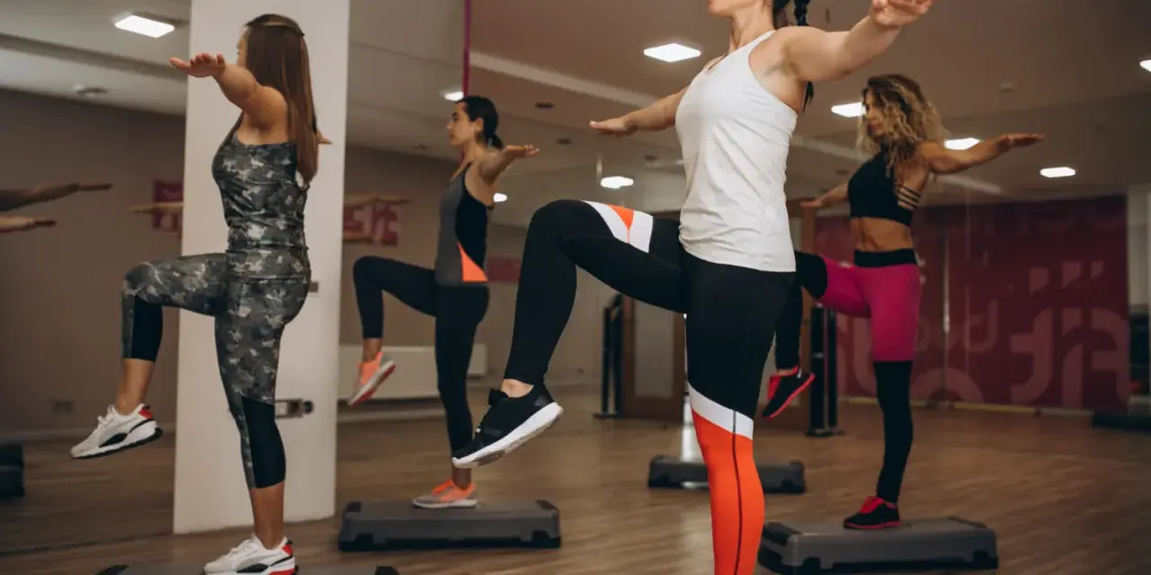 Kobiety na stepach wykonują trening aerobowy co to jest, ćwicząc równowagę i kondycję.