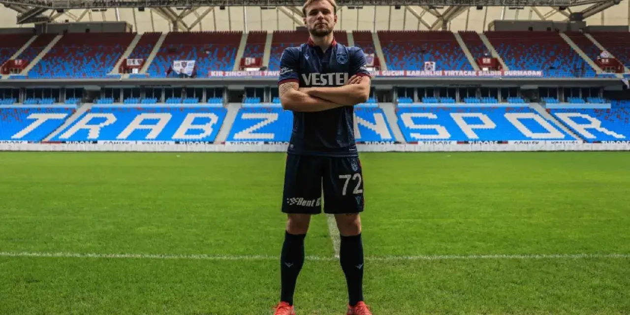 Piłkarz Tymek Puchacz w koszulce Trabzonspor z numerem 72, stoi na murawie stadionu.