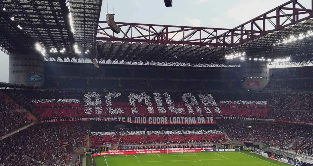 Trybuna stadionu San Siro w Mediolanie wypełniona kibicami AC Milan, tworzącymi napis "AC MILAN" i transparent "FOSSI DEI LEONI, VECCHIESTE IL MIO CUORE LONTANO DA TE".