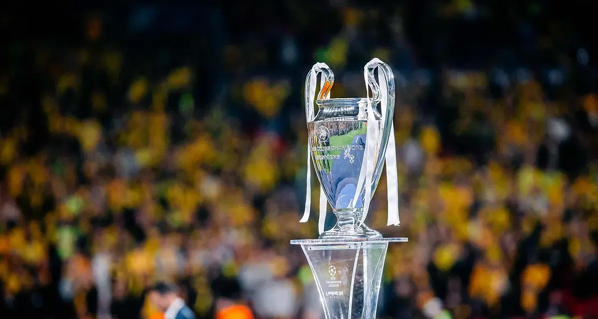Trofeum Ligi Mistrzów na podium, z tłumem kibiców w tle. Zastanawiasz się, ile za wygranie ligi mistrzów?