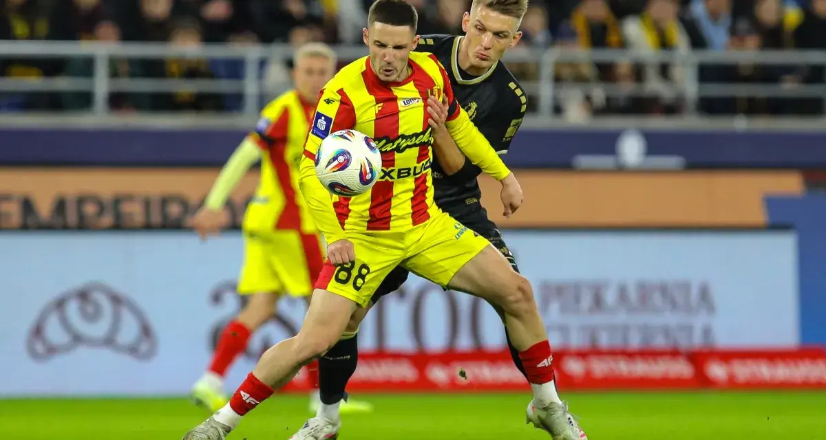Piłkarz w żółto-czerwonej koszulce walczy o piłkę z rywalem w czarnym stroju. Intensywny przebieg: Pogoń Szczecin – Korona Kielce.