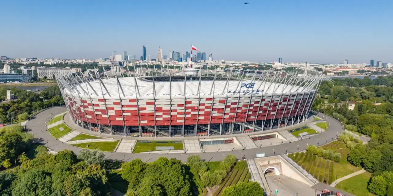 PGE Narodowy, jeden z największych stadionów w Polsce, w otoczeniu zieleni i warszawskiej panoramy.