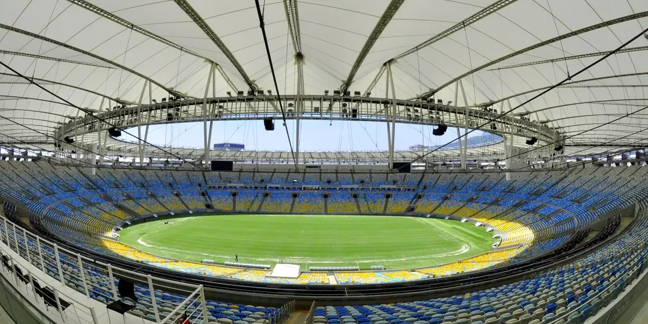 Pusta Marakana, stadion w Rio de Janeiro, z zieloną murawą i żółto-niebieskimi siedzeniami pod białym dachem.