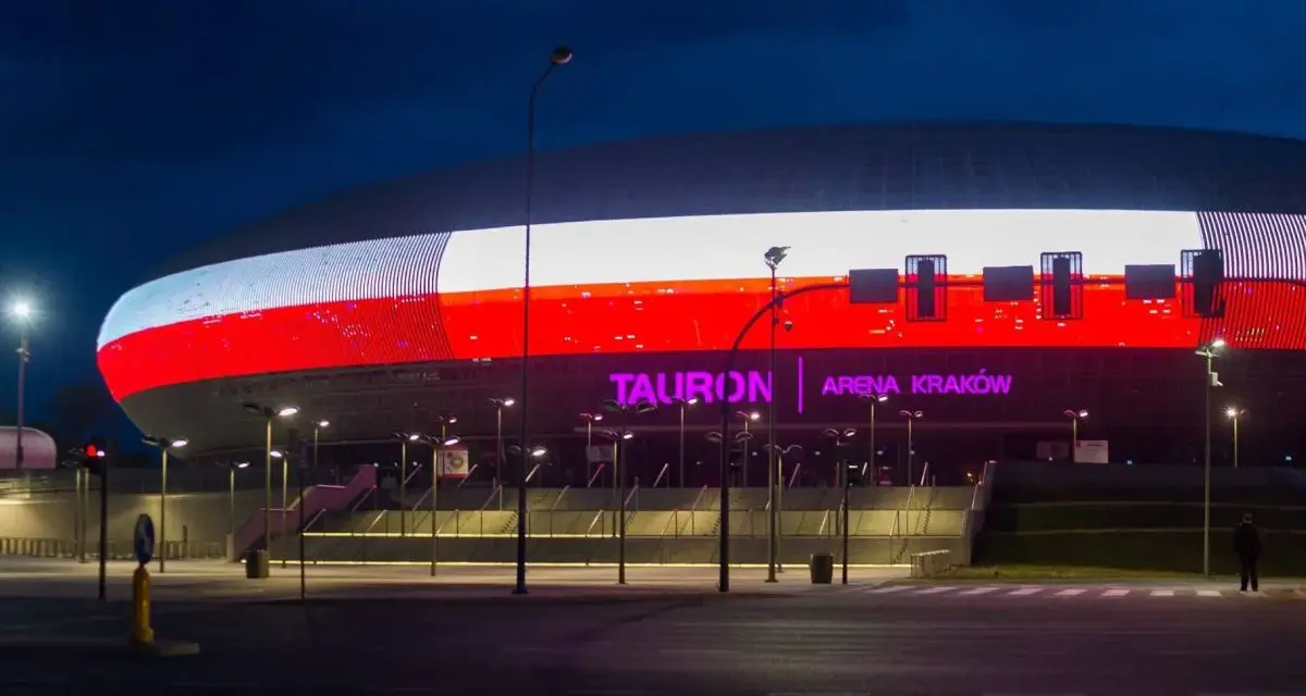 Tauron Arena Kraków nocą, z podświetloną fasadą w barwach narodowych. Obiekt mieści 15 tysięcy widzów, co czyni go jednym z największych w Polsce.