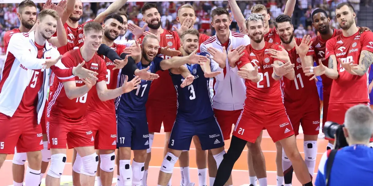 Uśmiechnięci siatkarze polski w czerwonych strojach pozują do zdjęcia, ciesząc się zwycięstwem.